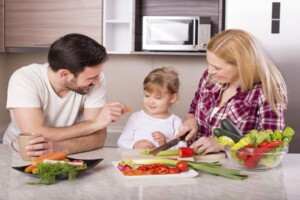 Rodzice uczący dziecko zasad zrównoważonego odżywiania poprzez wspólne przygotowywanie posiłków