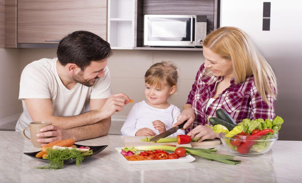 Rodzice uczący dziecko zasad zrównoważonego odżywiania poprzez wspólne przygotowywanie posiłków